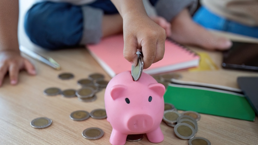 girl puts coins into a piggy bank