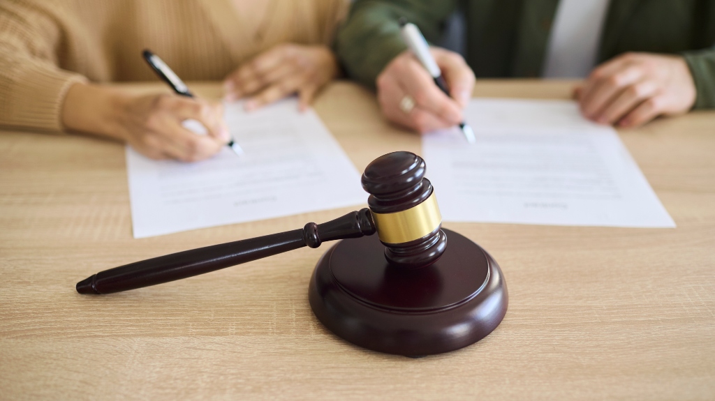 Couple signing divorce document at court with gavel